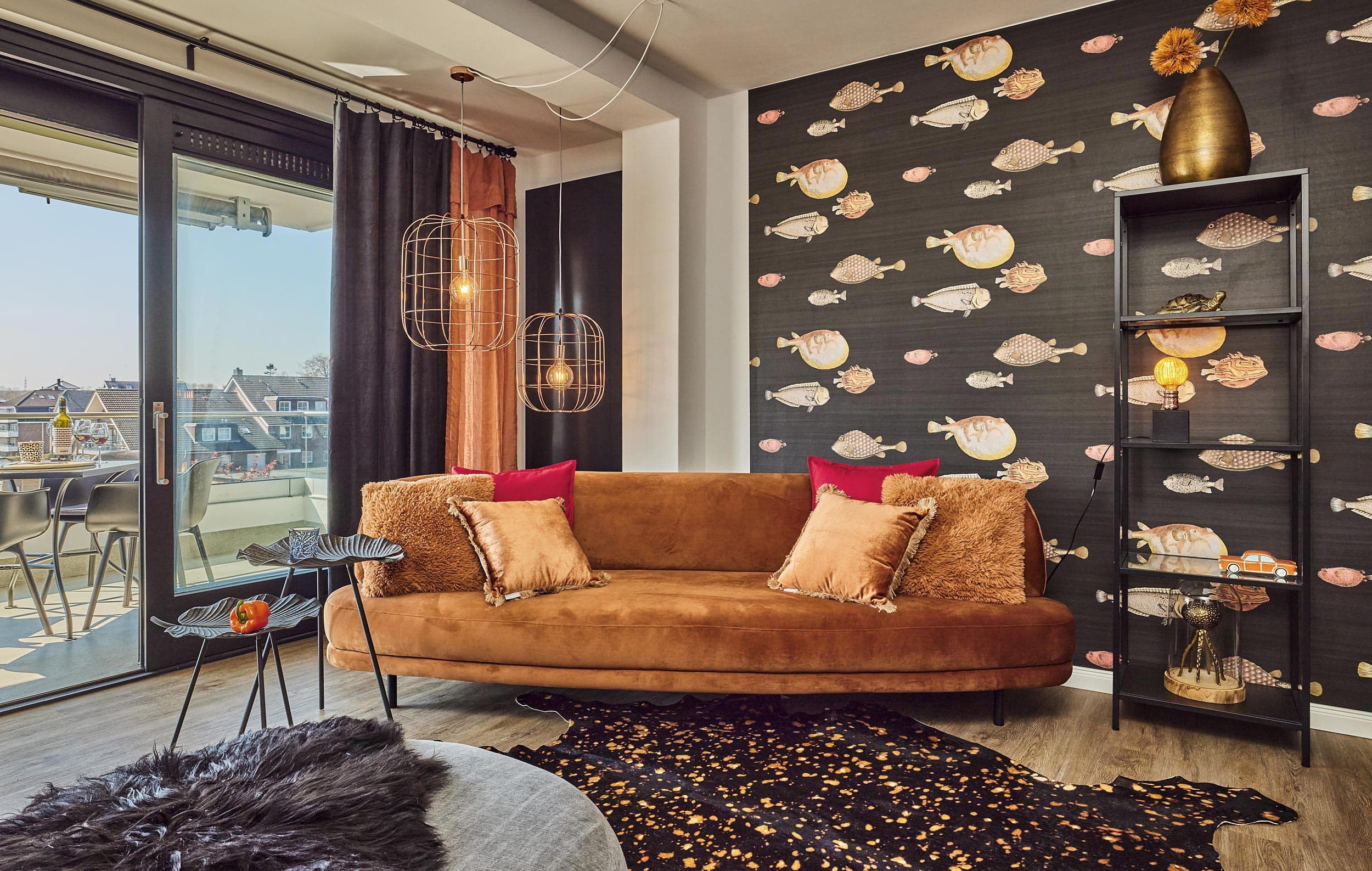I-LOVE-HOME-Ferienwohnung-Sofa_RET Curry farbiges Sofa vor einer dekorativen Fisch Tapete. Die Farben sind Anthrazit rot und ein dunkles Orange